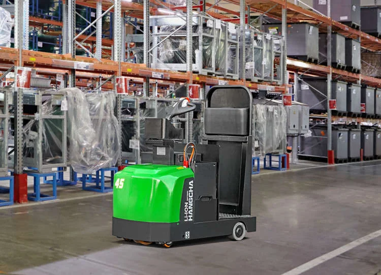 Hangcha A Series lithium tow tractor driving along a warehouse aisle past racking