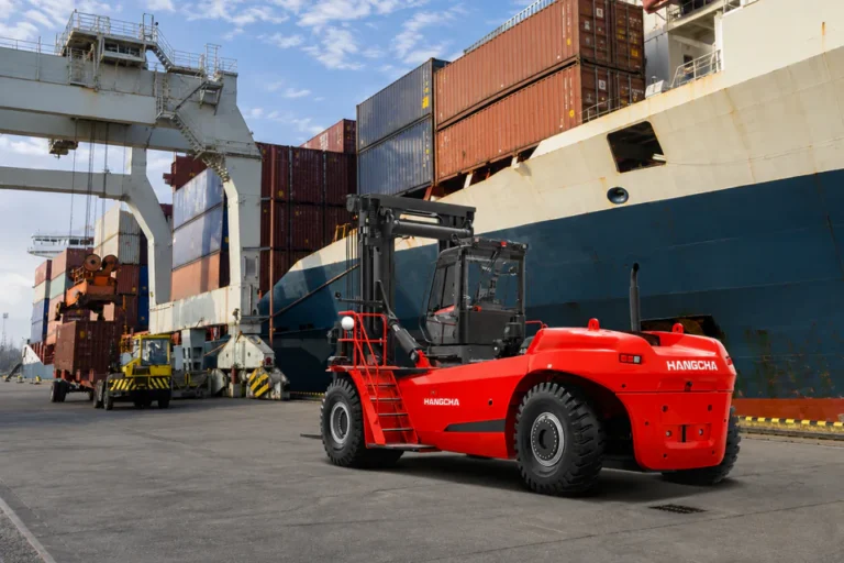 Red Hangcha heavy-duty forklift beside a container ship in an outdoor loading yard